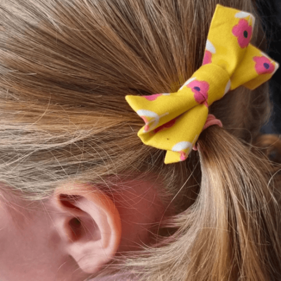 barrette noeud Barrette jaune à fleurs roses en forme de nœud dans les cheveux d'une petite fille.